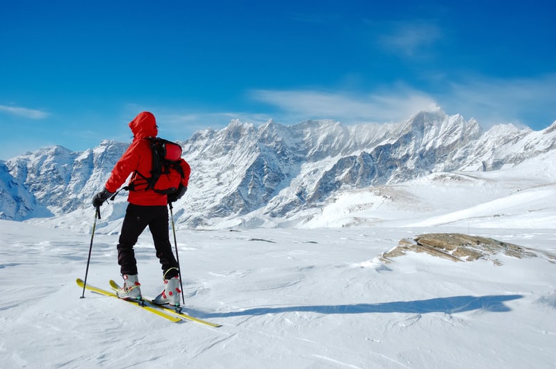 A lonely backcountry skier in a sunny winter day, alpine scenic, skiing in liechtenstein