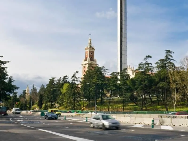 faro moncloa and museo americas, a road with trees with cars passing by with a building at the back