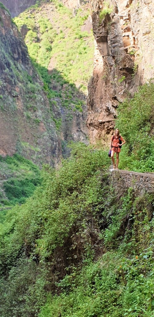 a woman posing near a cliff and near grass while hiking in santo antao, xoxo village