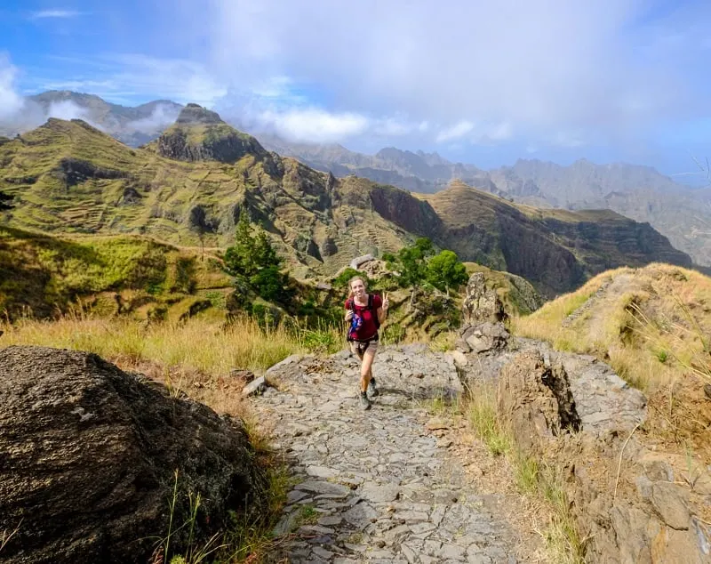 a woman walking on a paved trail at espongeiro coculi with terraces and mountains at the back