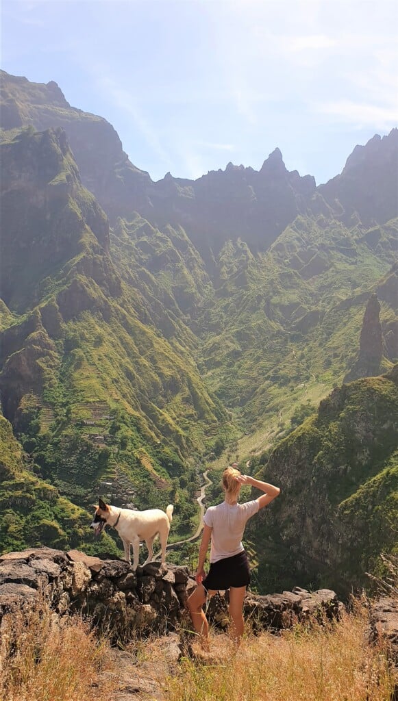 a woman on her back with a dog looking at views on hike corda marrador while hiking in santo antao