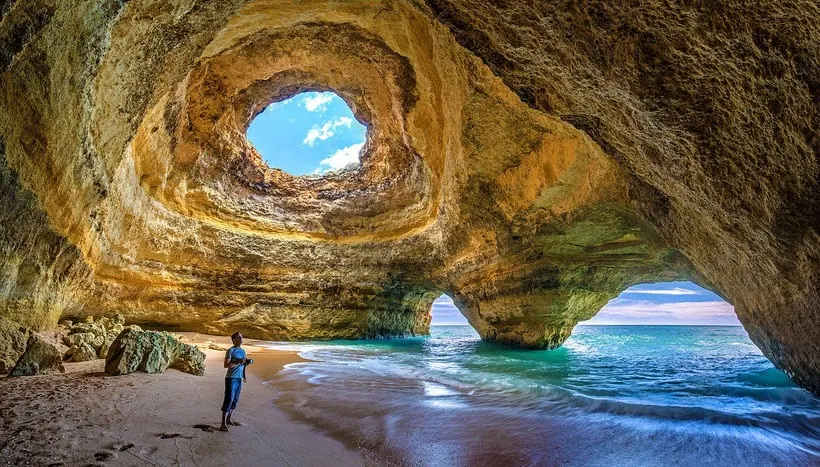 best things to do in algarve, person standing in a cave over the water with a sunroof