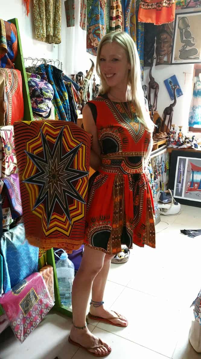 a woman on a colorful dress showing a colorful cape inside a shop in Cape Verde