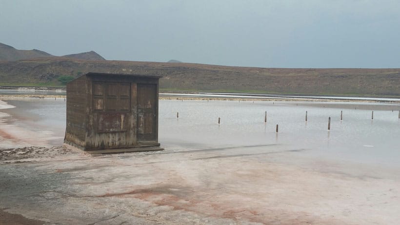 Read up on the things to do in santa maria cape verde, wooden hut next to flooded area of land with long hillside behind