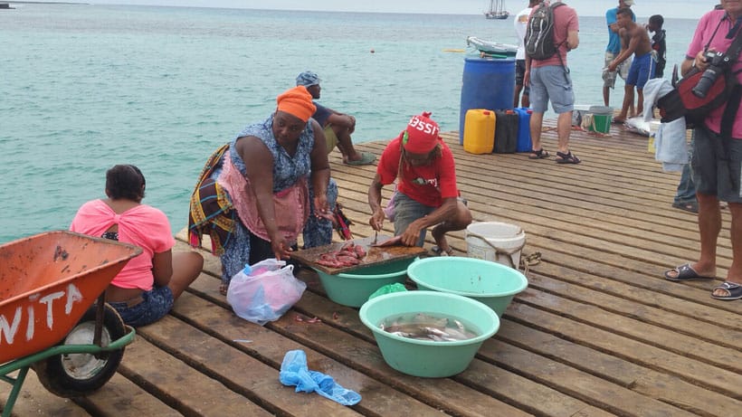 people in a fishing port selling, cleaning, and buying fish