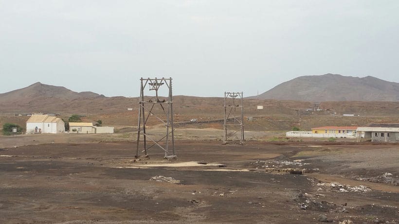 Plan out what to do on sal cape verde, white buildings and wooden towers standing amidst a wide open plain with tall hills in the distance