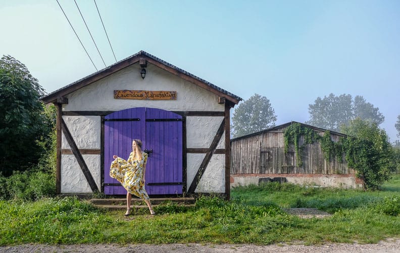 a woman posing in front of a barn house with a purple door at the Lavender Farm