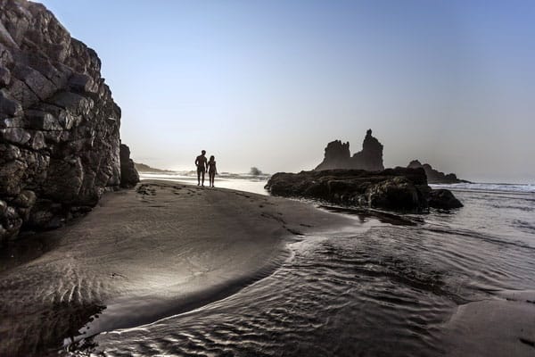 most beautiful places in tenerife, couple walking along black sandy beach