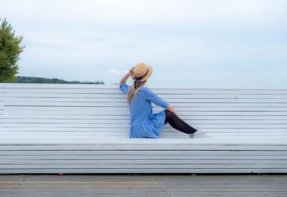 a woman hanging out in sopot by sitting on a bench ang looking at the sky