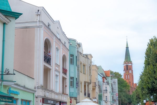 colourful houses in sopot with a cathedral tower and tree at the back