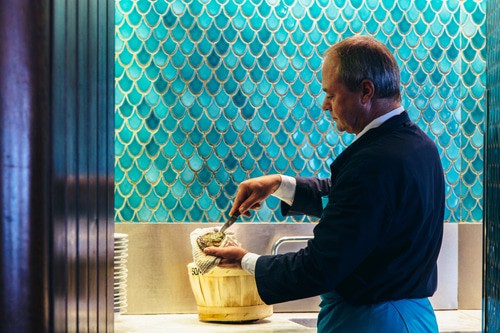 best belgian restaurants in brussels, man serving food into a bowl in front of a wall painted to look like blue fins