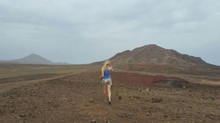 a woman walking up to a trail heading to a mountain