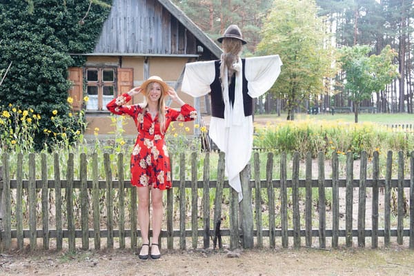 a woman posing beside a scarecrow