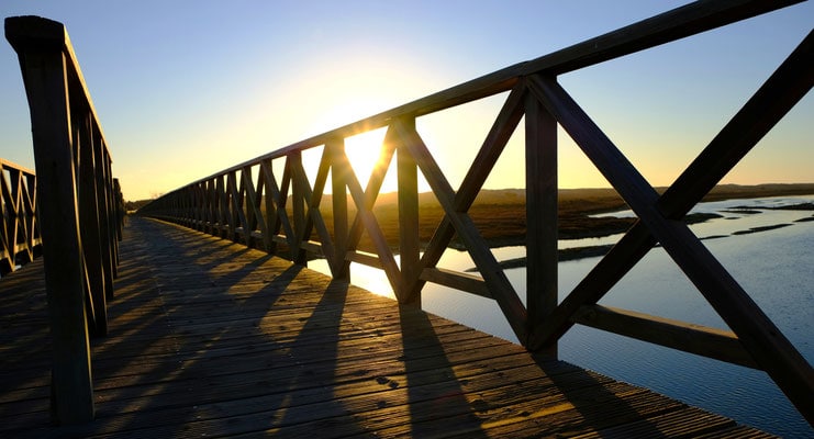 winter holidays in algarve, winter sun peaking out through wooden bridge