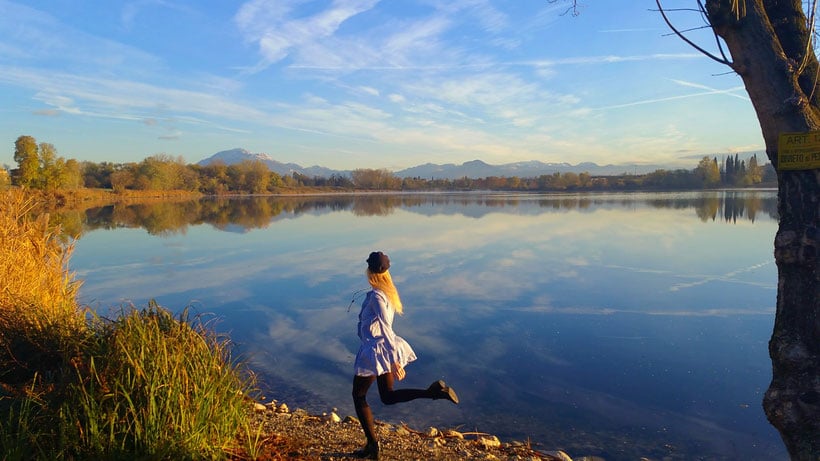 a woman running by a lake on a bright day