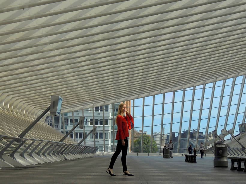 a woman wearing red posing inside a part of a train station in liege