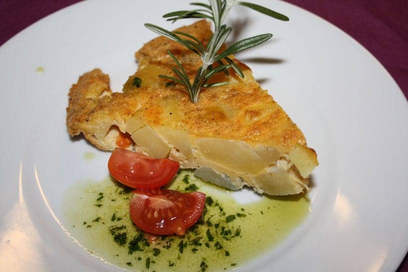 popular food in madrid, plate of pincho de tortilla  with tomatoes