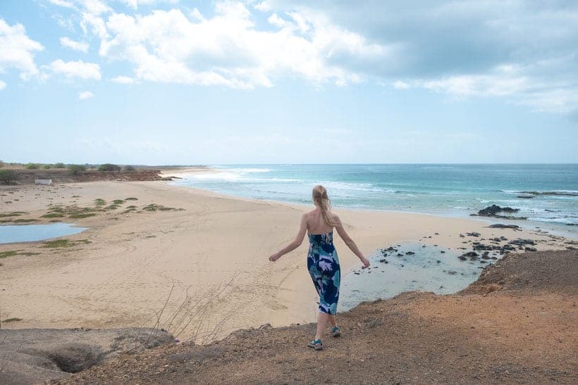 a woman looking at a wide beach on a bright day