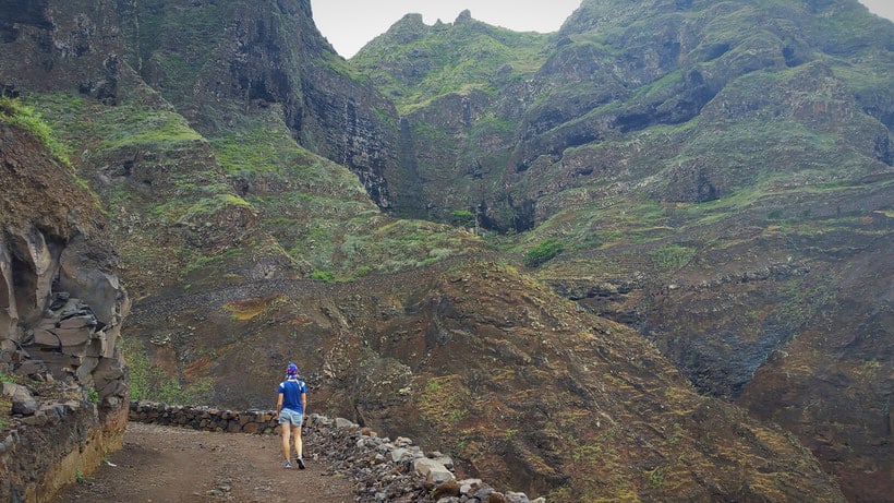 a woman hiking through a pathway with Valleys of Santo Antao.