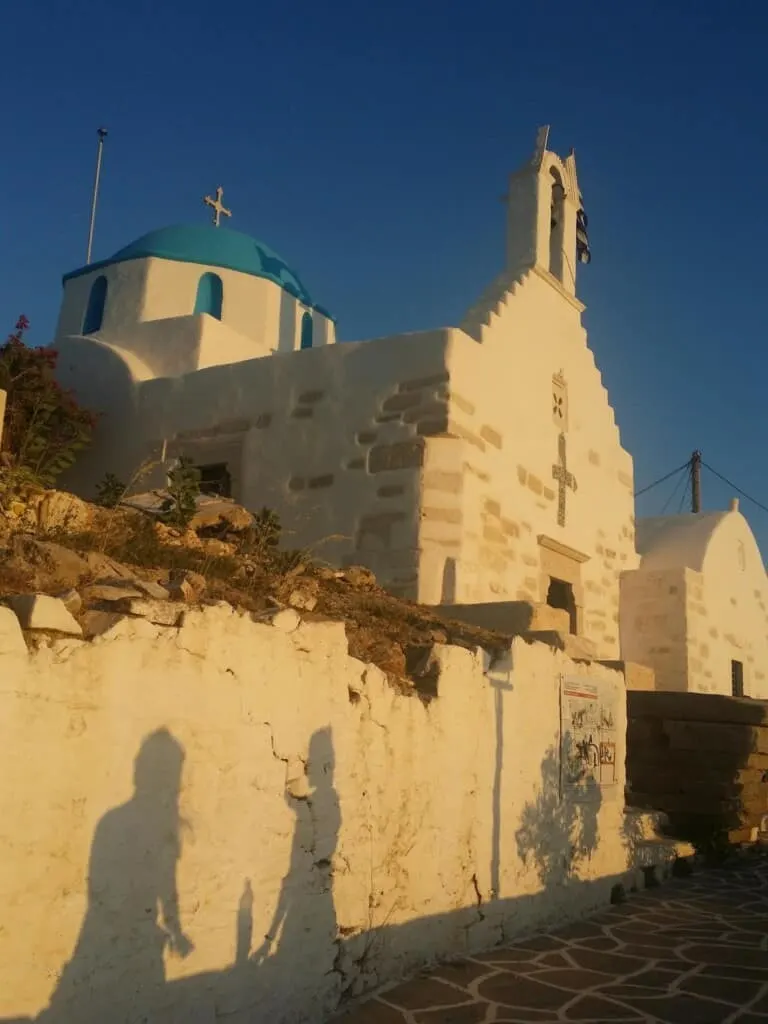 things to do in paros,greece, shadow on building at sunset of two people talking