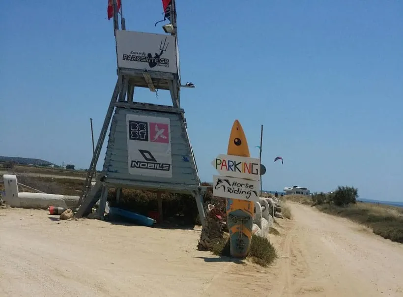 places to visit in paros, lifeguard tower and surfboard advertising parking and horseback riding at pounta beach paros