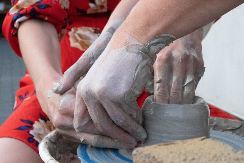 closeup of hands that are gray colored while making pottery