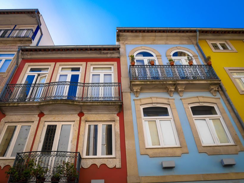 Cool Things To Do in Northern Portugal, view looking up at colorful buildings with awnings on a bright sunny day