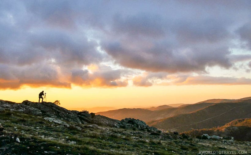 places to visit in north portugal, person setting up a tripod on a mountaintop overlooking over mountains at sunset