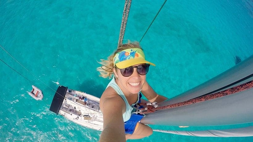 happy girl from a top of a sail on a sailing ship smiling on the camera