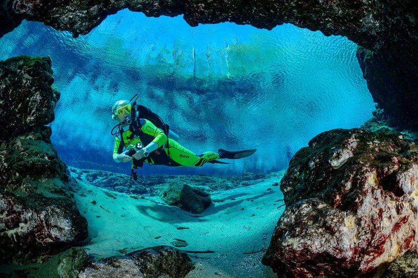 a scuba diver in the ocean looking at rocks