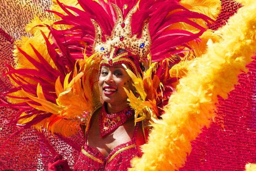 Spectacular attractions in Tenerife, smiling dancer dressed in red and yellow extravagant sequined costume with feathers and glittering jewelled crown