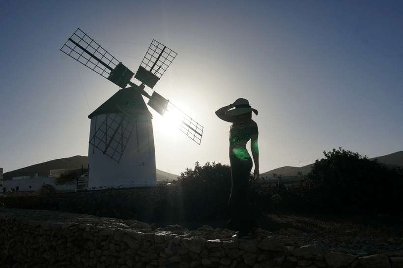 a windmill and a girl against the sun