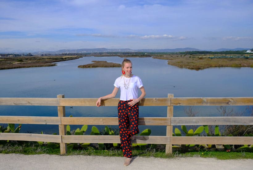 where to stay in algarve, hotels in algarve, accommodation in algarve, a woman standing on the center by a fence overlooking a lagoon