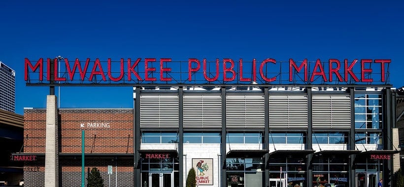 romantic spots in Milwaukee, street view of front of Milwaukee Public Market building with large neon sign on the roof on a bright clear day