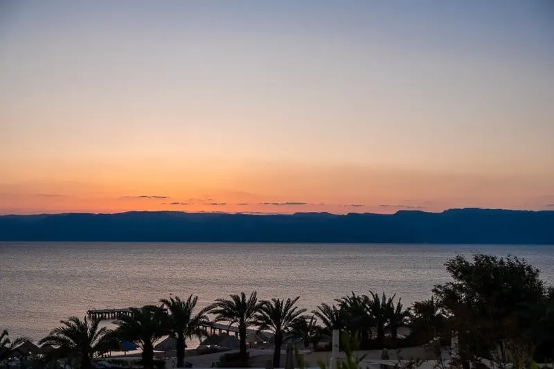 landscape view of a beach with palm trees on a sunset, jordan 10 day itinerary, what to do in jordan, things to do in jordan, petra, aqaba, jordan hotels amman, jerash, dead sea, spa, luxury hotels, wadi rum, diving, hiking, treasury, amman, jerash, dead sea, spa, wellness, luxury