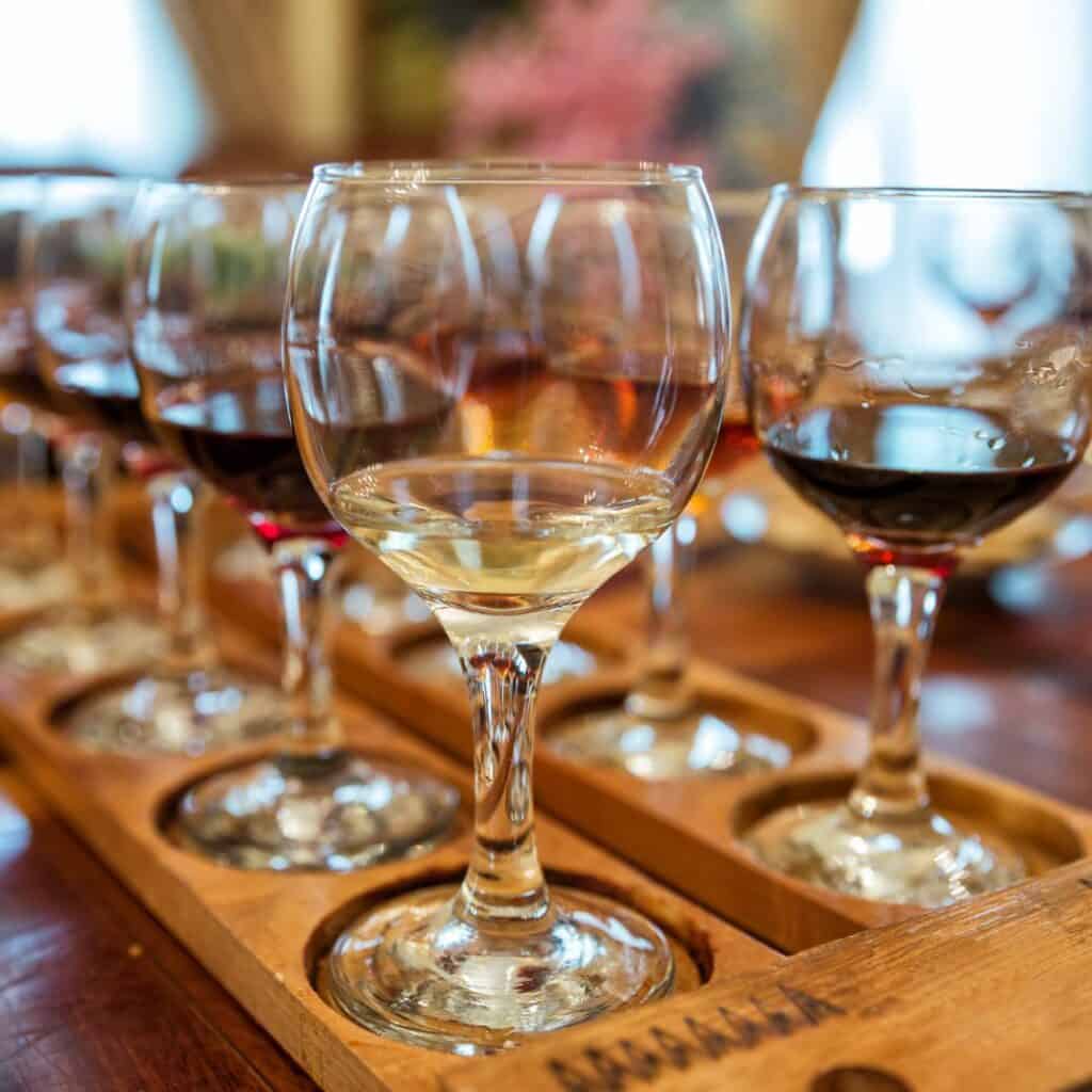 several wine glasses are lined up on a wooden tray for wine tasting in a cafe or restaurant