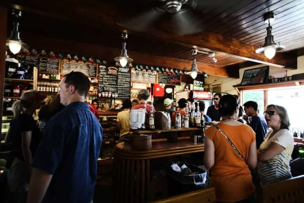 Check out these things to do in fall in Milwaukee, interior of sports bar with people standing and talking in groups in front of the bar area with low ceiling and ornamental lights