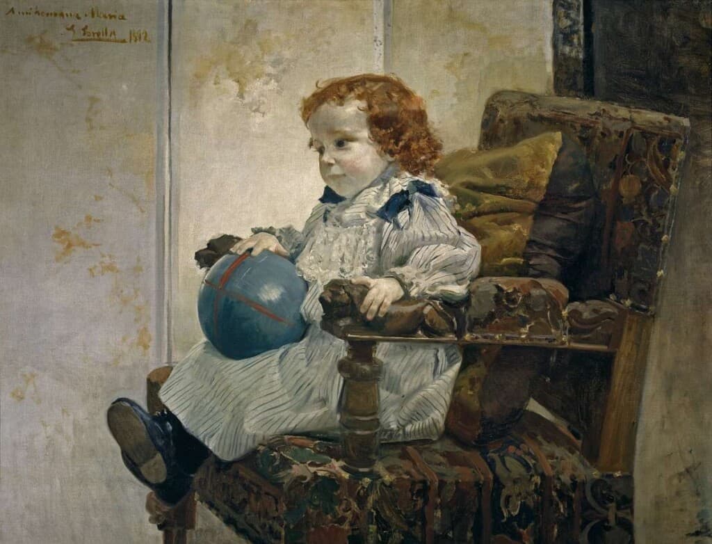 A painting of a young child holding a blue ball and sitting in a chair. The child has curly red hair and is wearing black shoes. He is slightly smiling. Joaquin Sorolla Bastida did this painting.