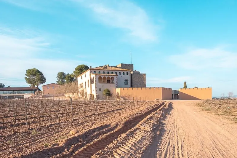 what looks like a desert with a house, wine tour barcelona, wineries near barcelona, Cava Tasting inoller del mas, champagne tasting, catalonia, winery, vineyards, montserrat, red wine, white whine, medieval castle