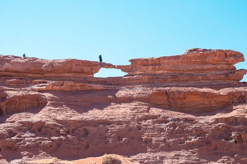 Find the best places to see Wadi Rum in the best light, large rock formations with person standing on small platform in the middle under a clear sky