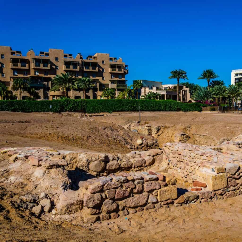 ruins of an old city on sand with houses at the back