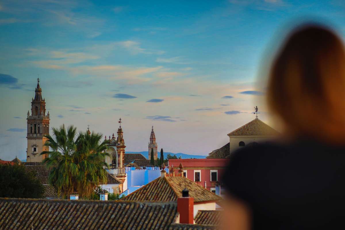a picture of a blurry woman looking at Ecija town view from the 2nd floor roofs and towers of churches and buildings are seen