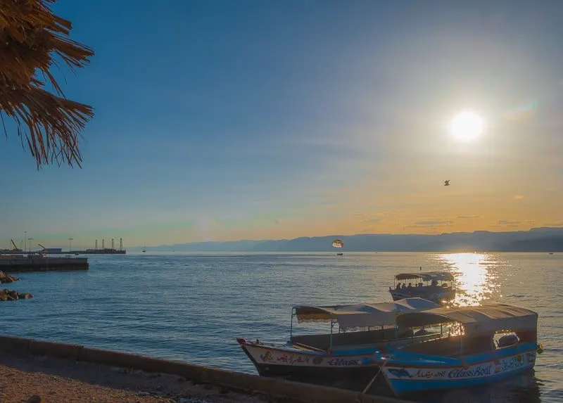 two boats anchored in the sea during a sunset, things to do in aqaba, jordan, red sea, wadi rum day trip, petra day tour, resorts, ayla oasis, souk, shopping, egypt, beaches, luxury, snorkeling, diving