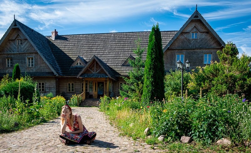 girl sitting in front of a wooden cabin in bialowieza, poland