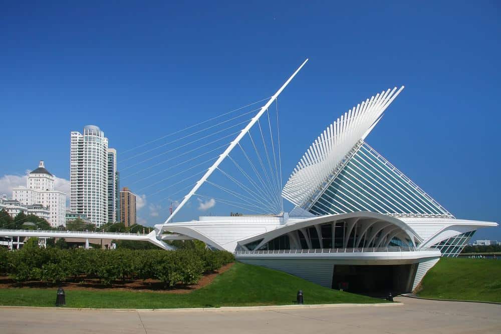 a weird looking white building on a grass with other buildings on the background