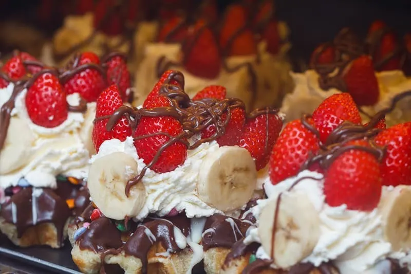 Tasty Christmas food in Belgium, Belgian waffles with whipped cream, chocolate and strawberries on the display case