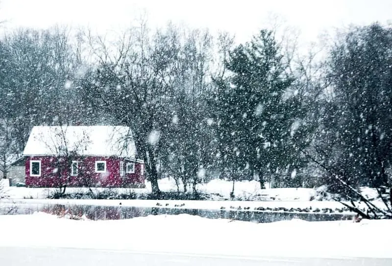 Winter Getaways in Wisconsin, cabin on a lake surrounded by falling snow
