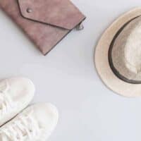 Flat lay travel items - shoes, hat and purse on grey background