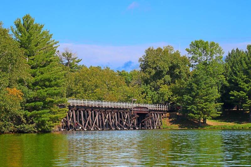 Rustic wooden trestle across the Bearskin State Trail in Minocqua Wisconsin surrounded by trees by a body of water