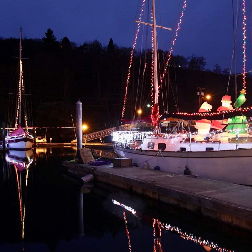 a boat is docked at a marina with christmas lights on it